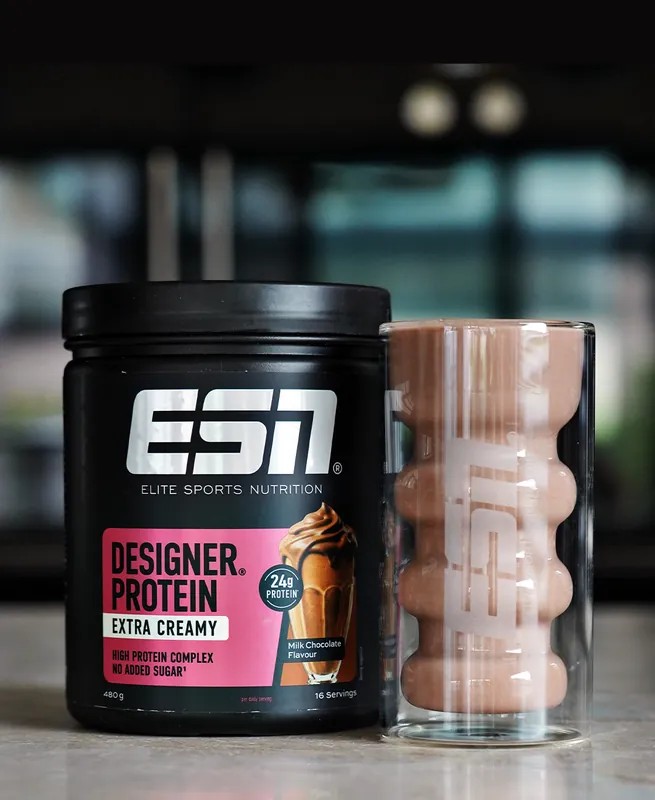 ESN Designer Protein Extra Creamy – Milk Chocolate, with a glass